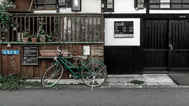 blue and green bicycle parked beside brown wooden house during daytime